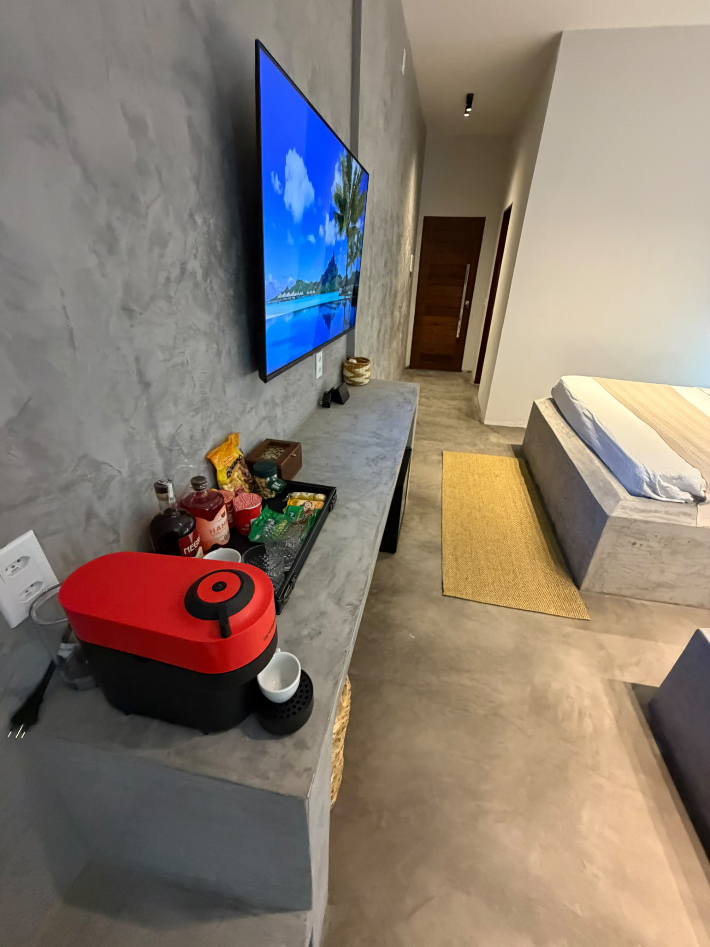 Bancada com TV, cafeteira e frigobar ao lado das camas