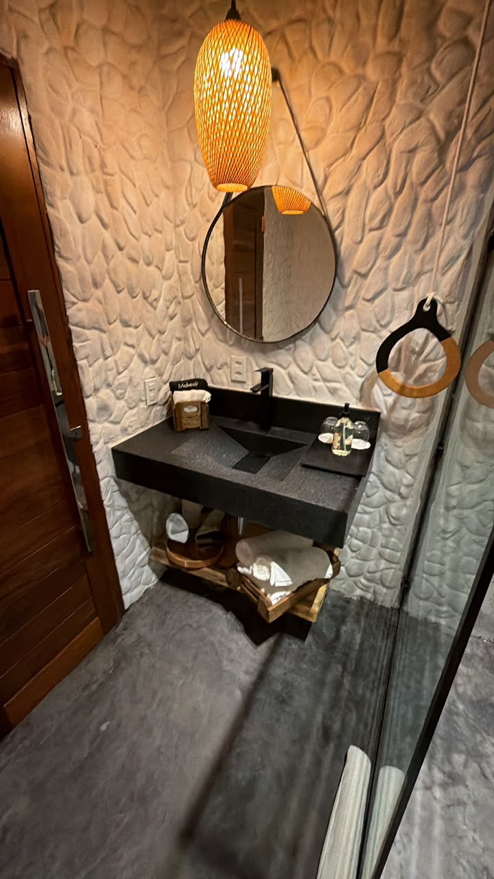 Lavabo com cuba de granito preto e luminária de palha