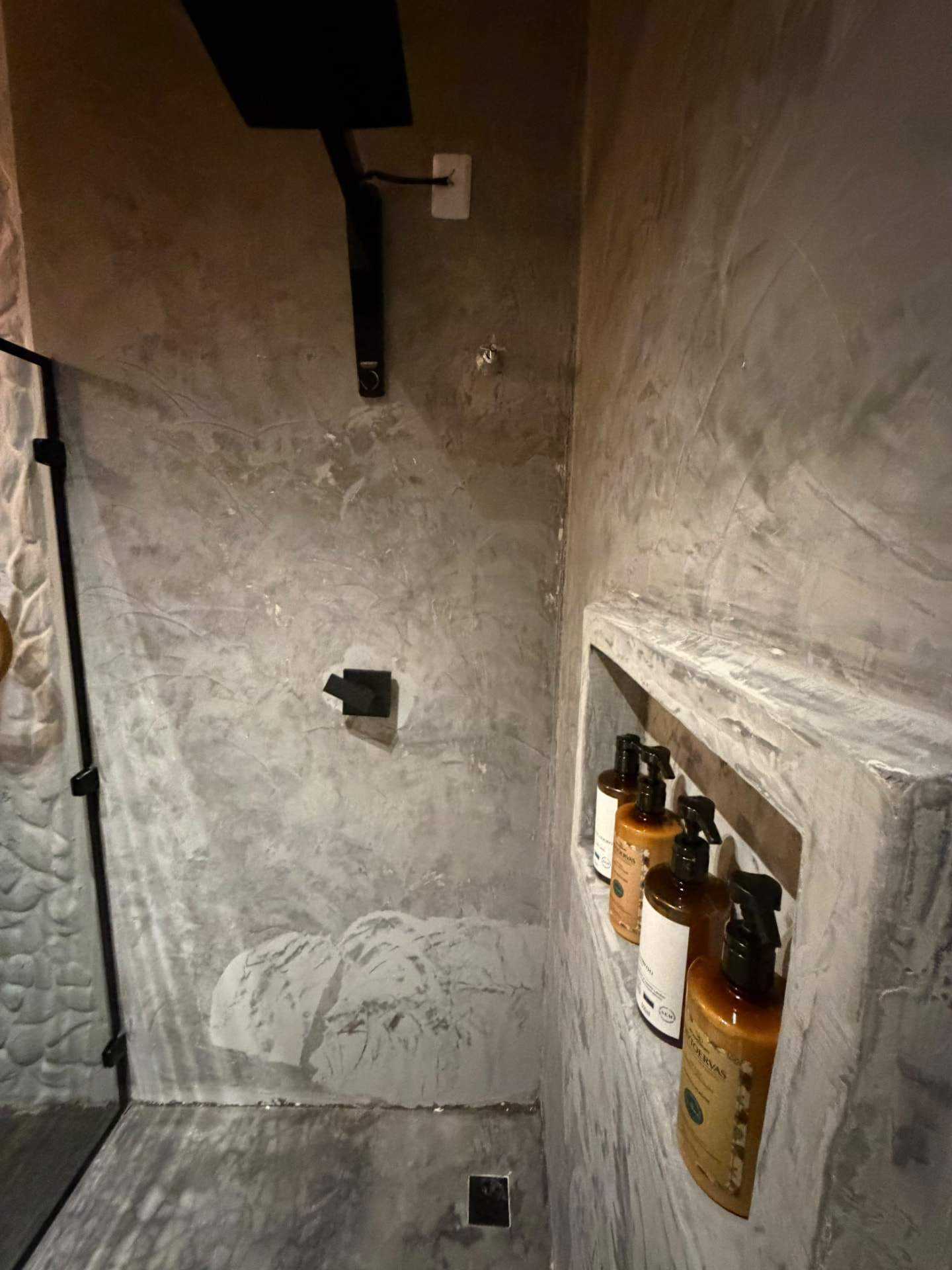 Box em cimento queimado com ducha preta e nicho de amenities