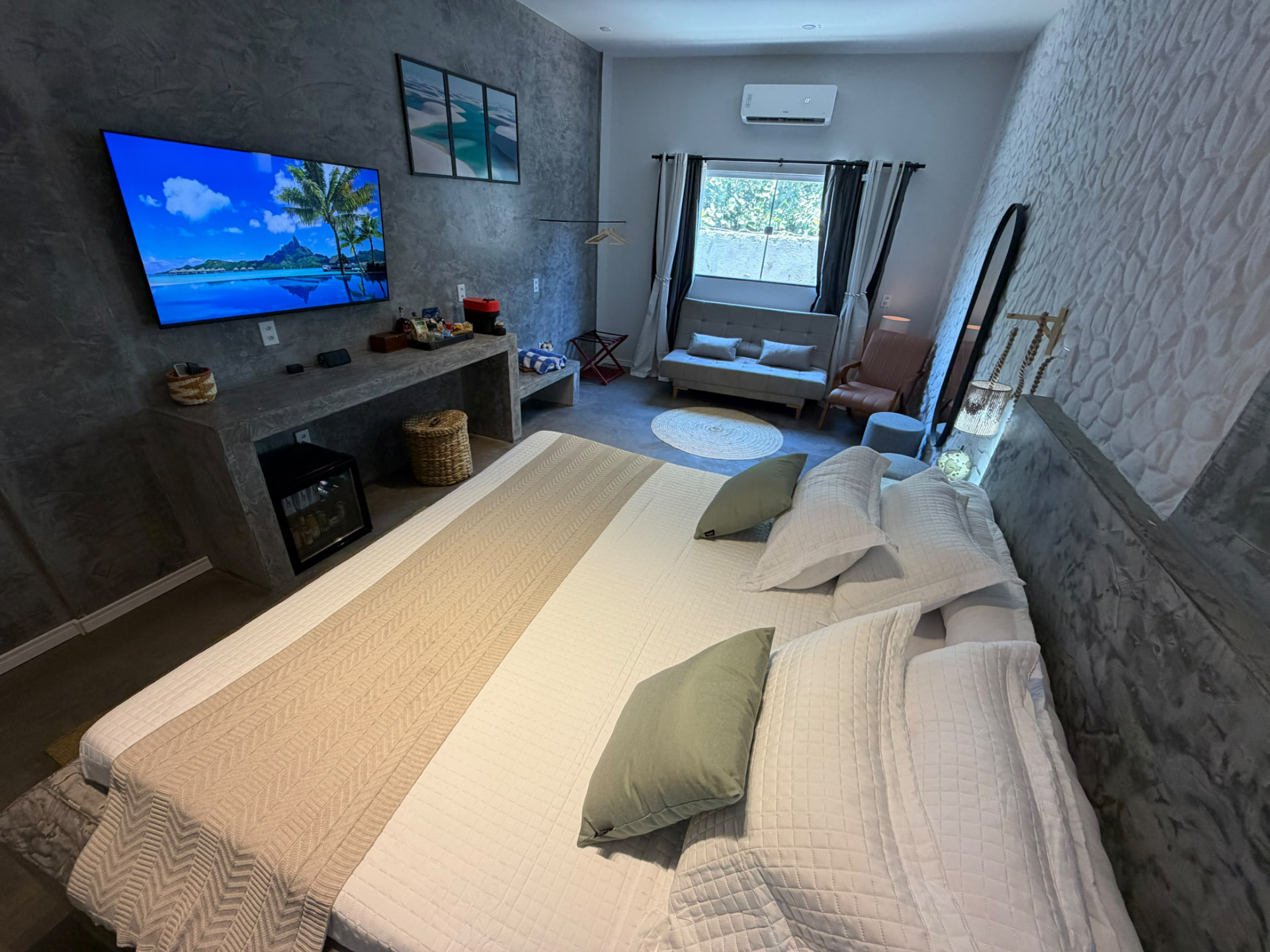 Cama king com sofá-cama, poltrona e janela ao fundo