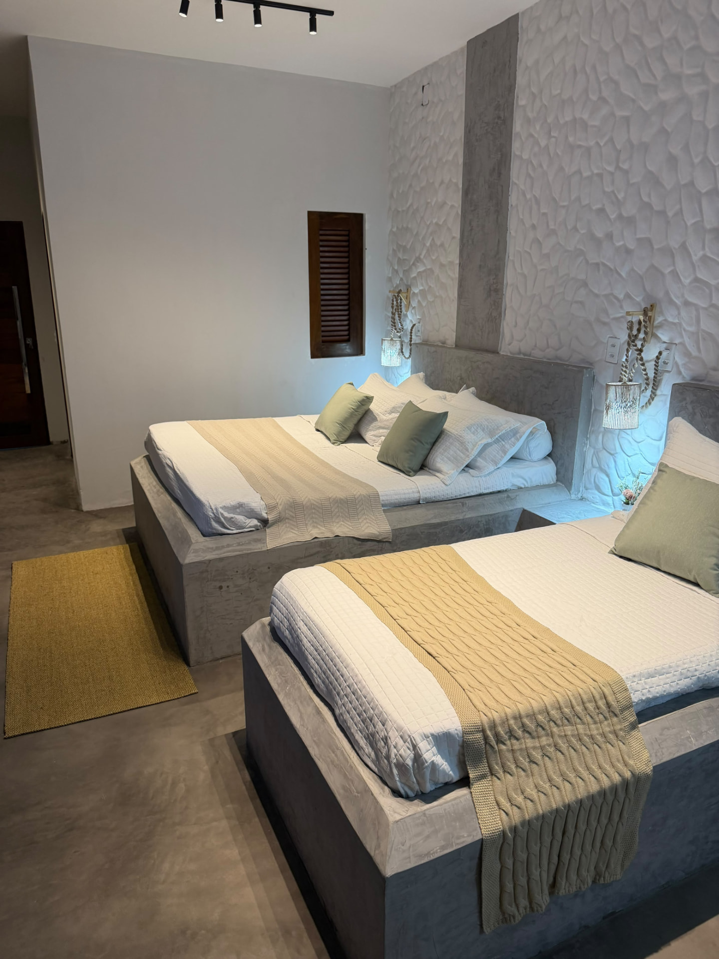 Quarto com duas camas, arandelas de corda e parede de pedra